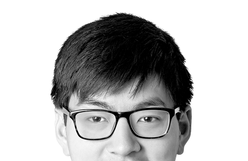 A person with short hair and glasses is smiling at the camera. We can see their eyes and nose, but the photo is cropped above their mouth.